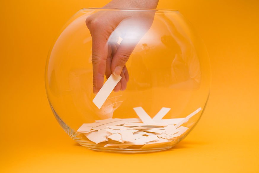 Hand reaching into a bowl to pick a lottery ticket